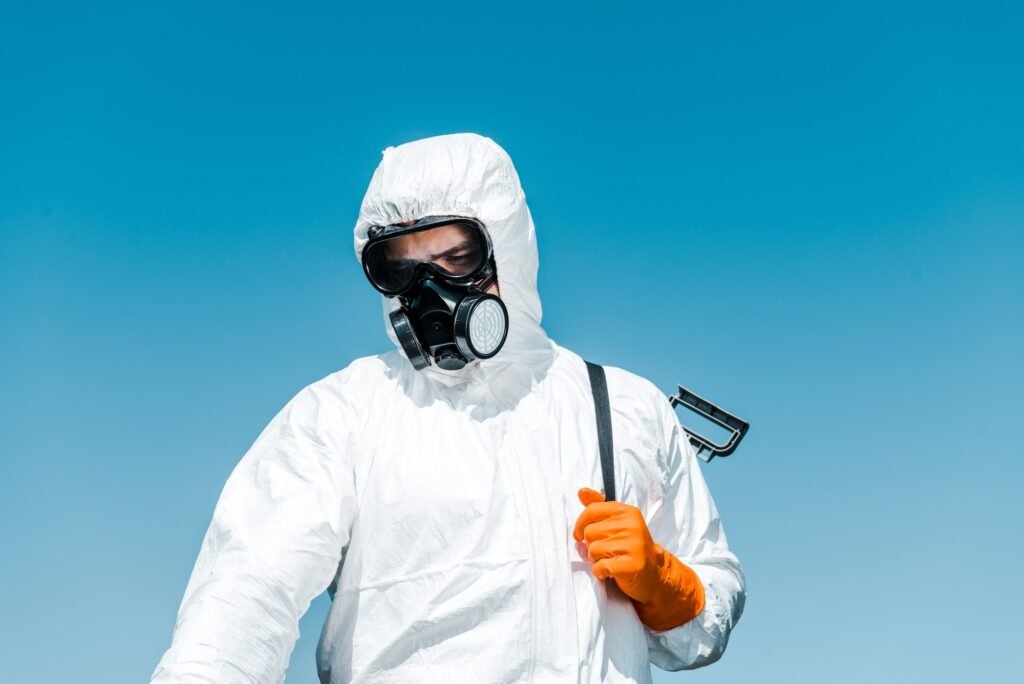 exterminator in white uniform and latex glove holding spray